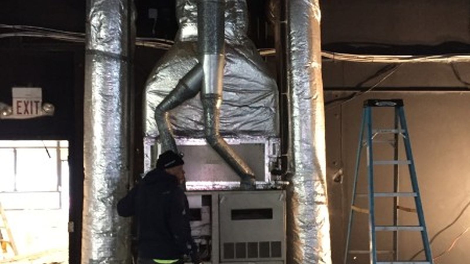 McGrath technician working on a commercial HVAC unit and insulated ductwork