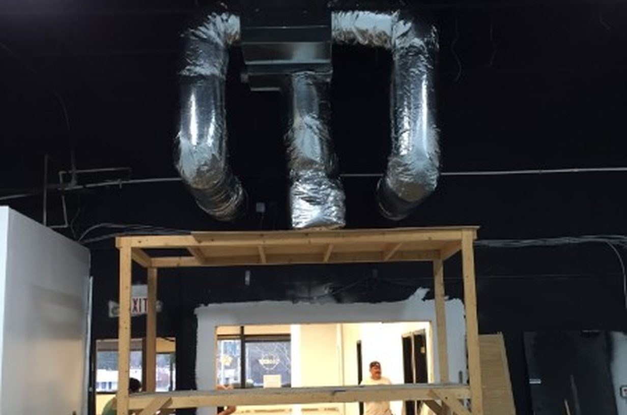 Insulated commercial ductwork being installed in a blacked-out interior