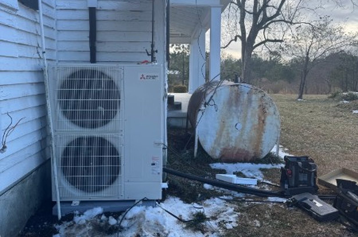 Mitsubishi Electric heat pump being installed beside a home